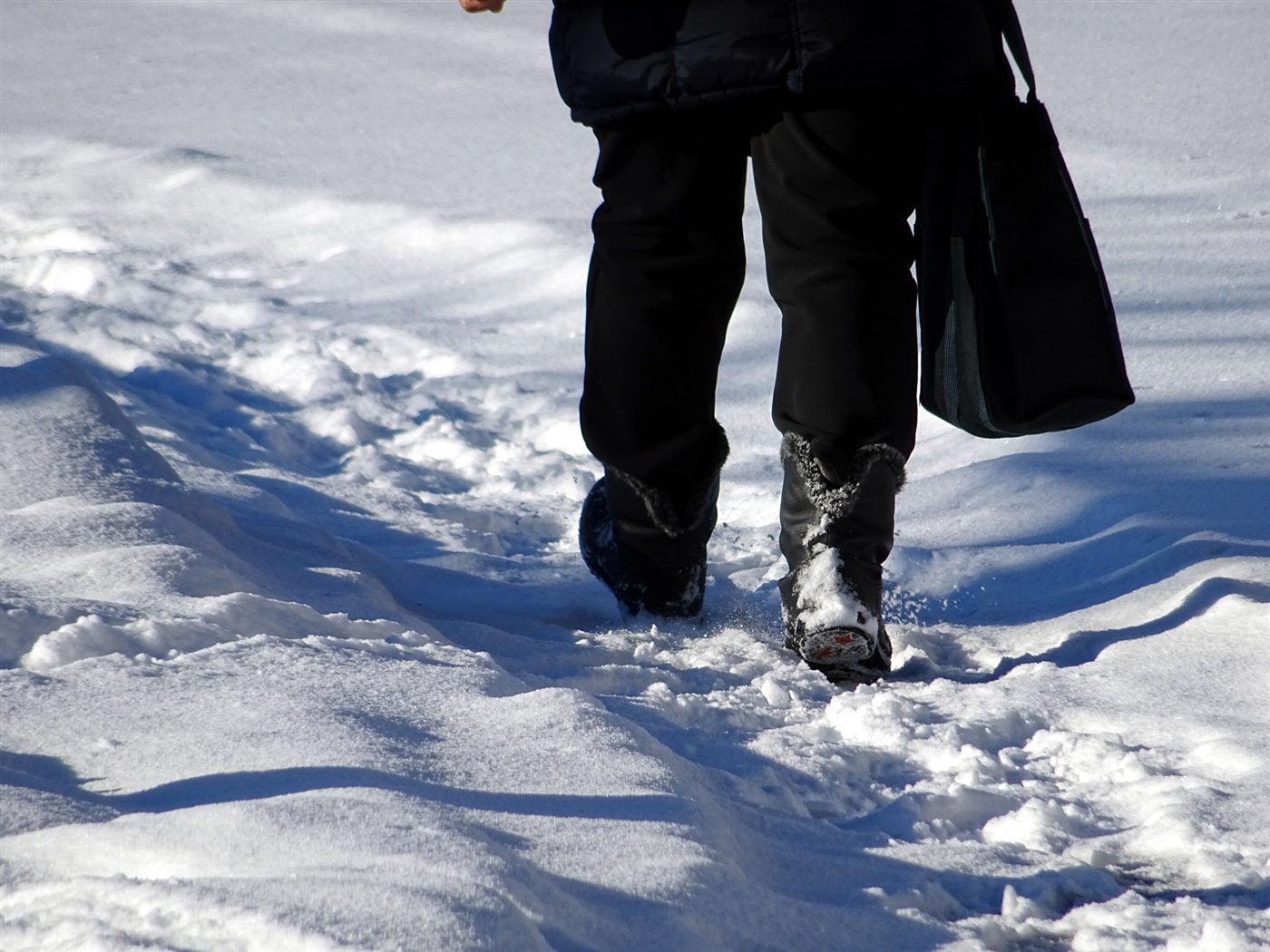 深い雪道を歩く人の足元